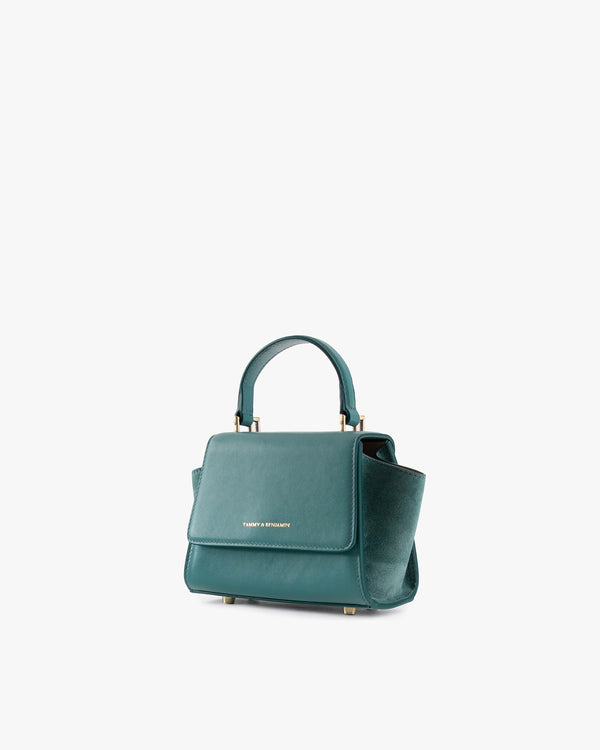 Sac ALEXIA NANO turquoise, vue de trois quarts, poignée courte, rabat fermé posé au sol