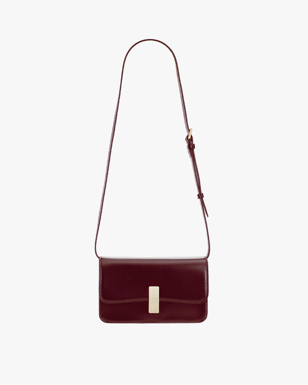 BLAKE bag in Mahogany, front view, laid flat with adjustable thin strap extended and gold clasp