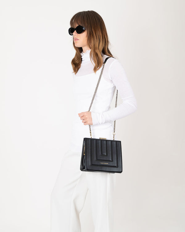 JUDE quilted black bag worn crossbody with chain strap, side view on model