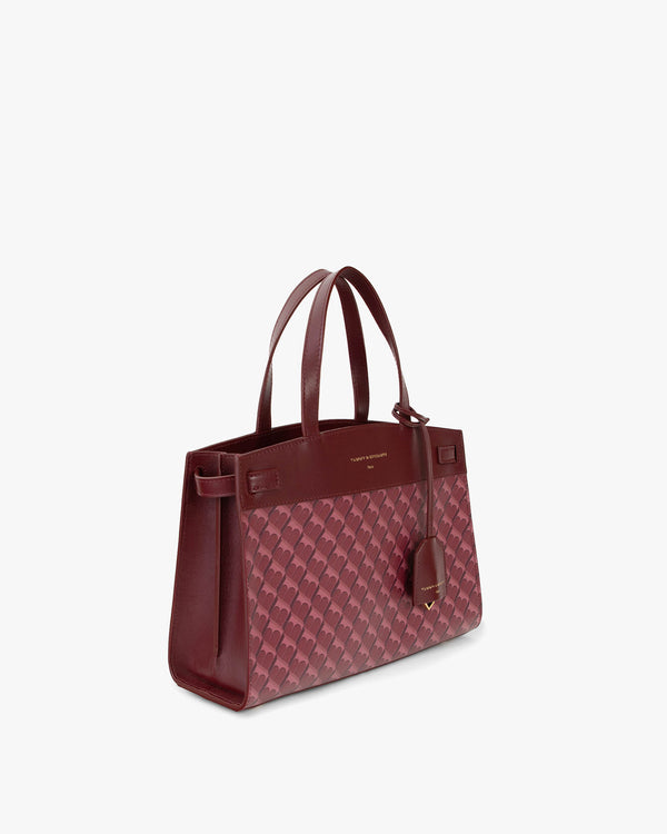 Sac MADISON Bordeaux vu de trois quarts, posé, anses courtes, motif monogramme et cuir lisse