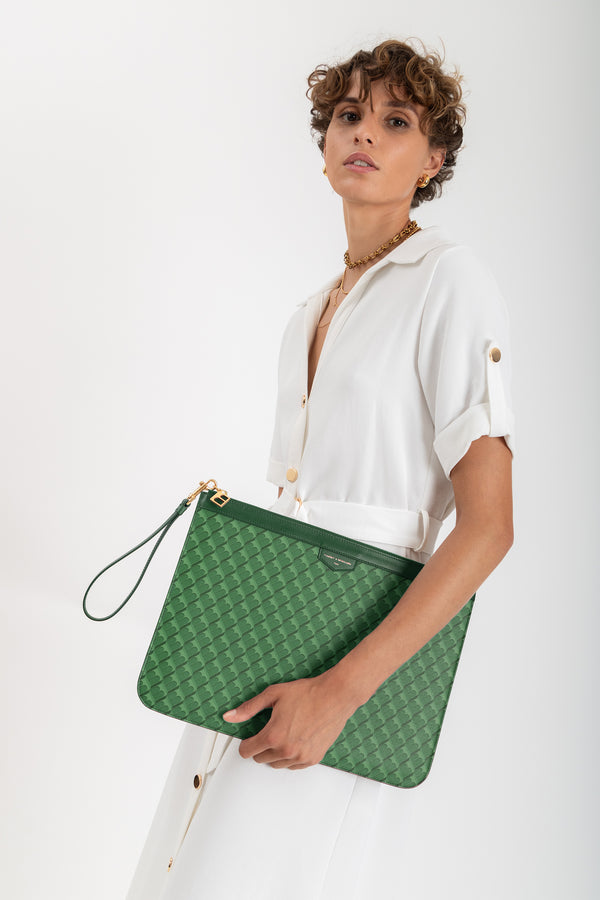 Pochette GM Monogram verte en toile enduite à motif, tenue à la main par la dragonne cuir