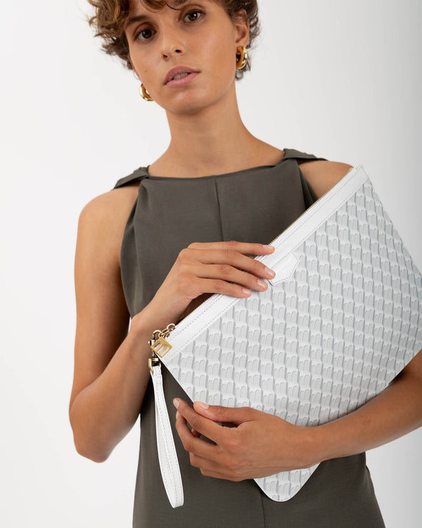 Pochette GM Monogram ivoire tenue sous le bras, zip et dragonne en cuir visibles