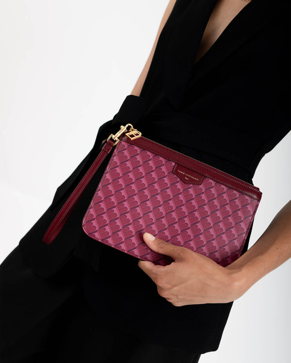Pochette PM Monogram Bordeaux tenue à la main par une femme en robe noire, dragonne en cuir