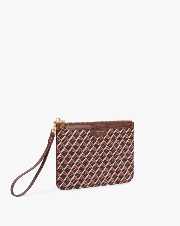 Pochette PM Monogram brun monogram, vue 3/4, posée, dragonne en cuir détachée devant, zip et breloque dorée visibles