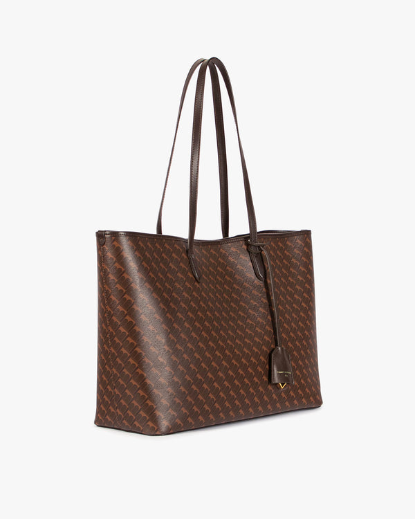 TOTE MONOGRAM Chocolat, vue de trois quarts, anses longues en cuir posées sur l'épaule
