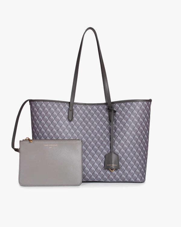 Sac TOTE MONOGRAM gris posé de face avec sa pochette amovible, anses en cuir, motif monogram