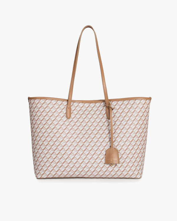 Sac TOTE MONOGRAM Tan posé de face, anses longues en cuir, motif monogramme sur toile enduite