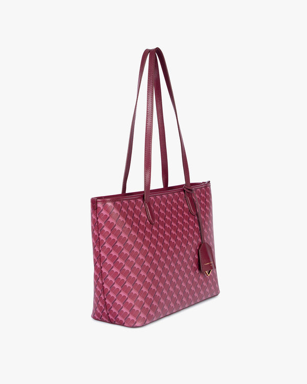 Sac TOTE MONOGRAM PM Bordeaux, vue de profil porté à l'épaule, anses plates et porte-étiquette apparents