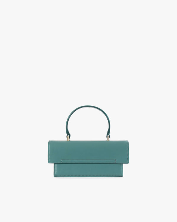 Sac THEA MINI turquoise de face, rabat fermé, posé, avec anse courte rigide