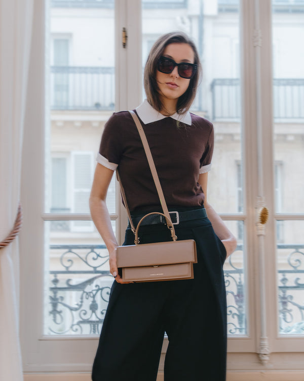 Sac THEA beige porté en bandoulière, tenu à la main, poignée rigide, fermoir doré visible
