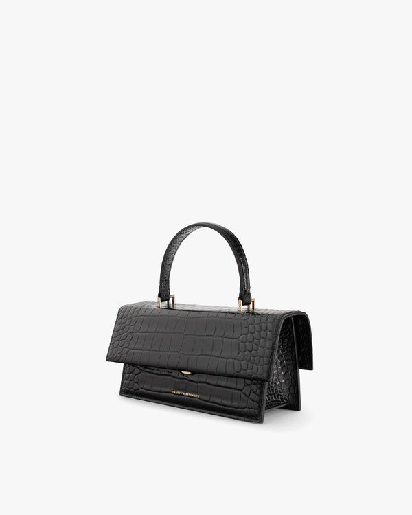 Sac THEA noir embossé crocodile, vue de trois quarts, poignée rigide, rabat oversize fermé