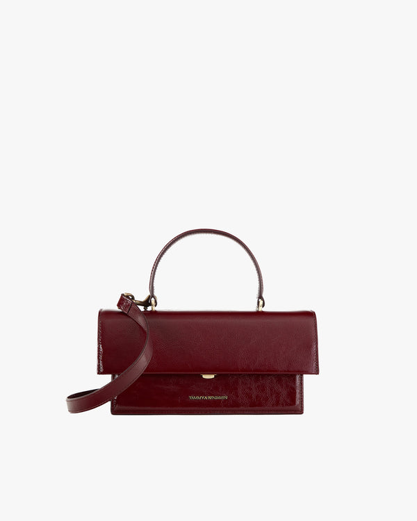 Sac THEA en cuir naplak bordeaux, vue de face, posé, avec rabat oversize et poignée rigide
