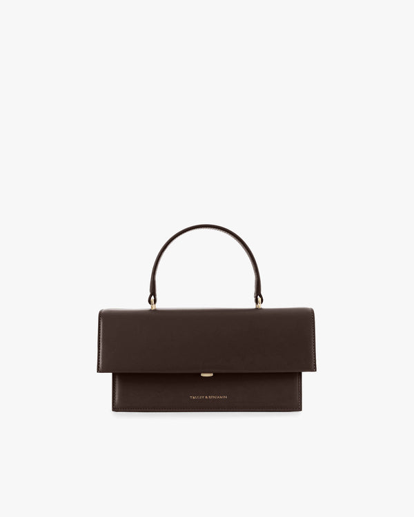 Sac THEA Chocolat de face, rabat oversize fermé, poignée rigide, posé sur fond blanc