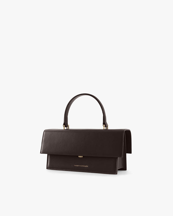 Sac THEA Chocolat de trois quarts, rabat fermé, poignée rigide tenue haute, fond blanc