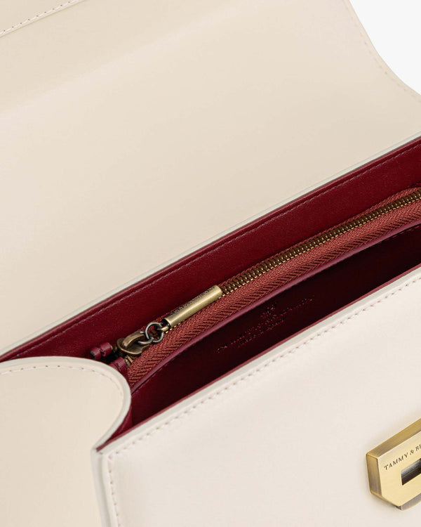 Sac THEA Ivoire, vue intérieure sur la poche zippée à doublure bordeaux et fermoir doré