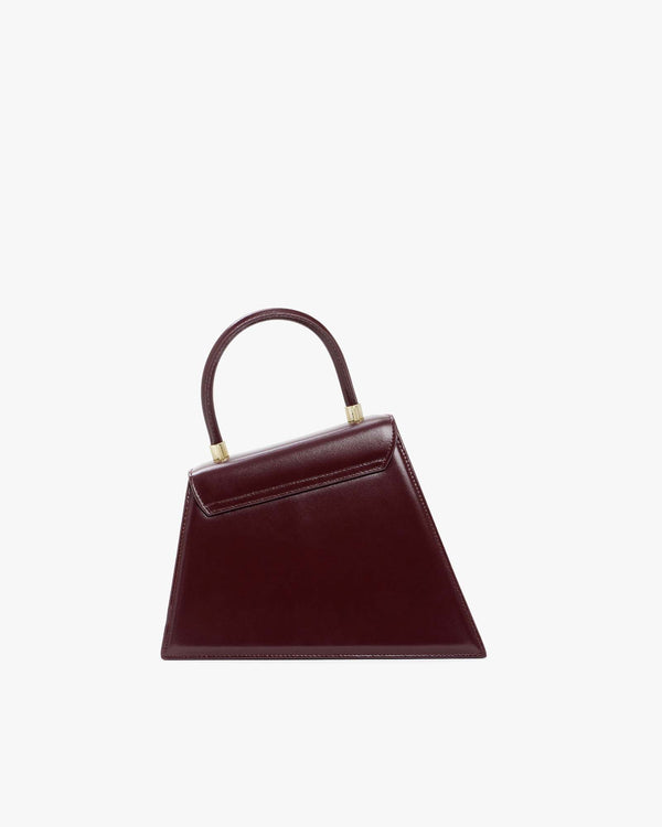 Sac CUBIST Mahogany de face, silhouette trapèze asymétrique, anse courte, poignée dorée