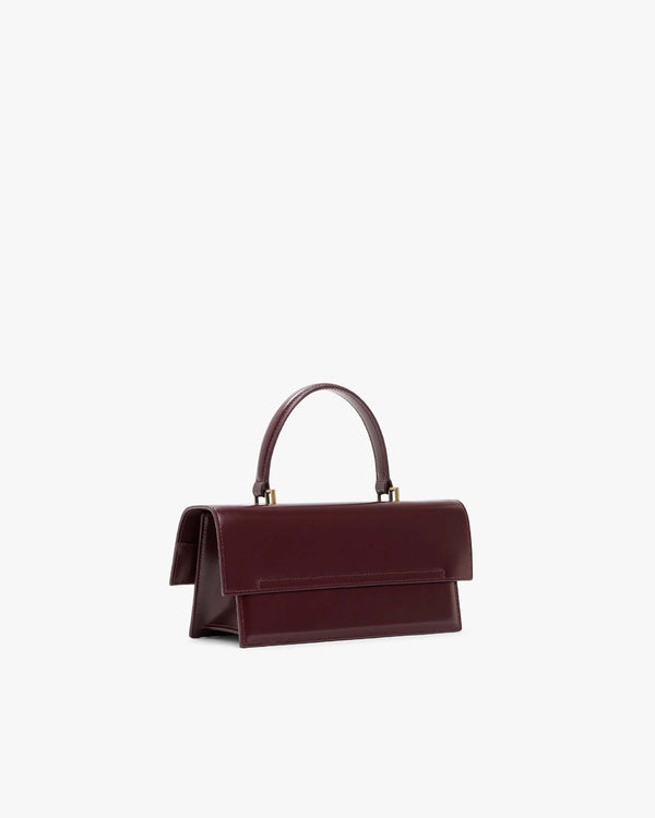 Sac THEA Mahogany, vue de trois quarts arrière, posé, rabat fermé, poignée rigide relevée
