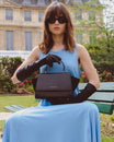 Sac ALEXIA noir porté à la main, tenu par sa poignée, assise sur un banc