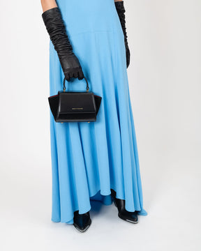 Sac ALEXIA NANO noir porté à la main, poignée rigide, vue de face sur robe bleue