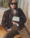 Sac ALEXIA NANO Colourblock art déco tenu à la main, porté avec veste en cuir marron