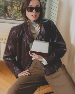 Sac ALEXIA NANO Colourblock art déco tenu à la main, porté avec veste en cuir marron