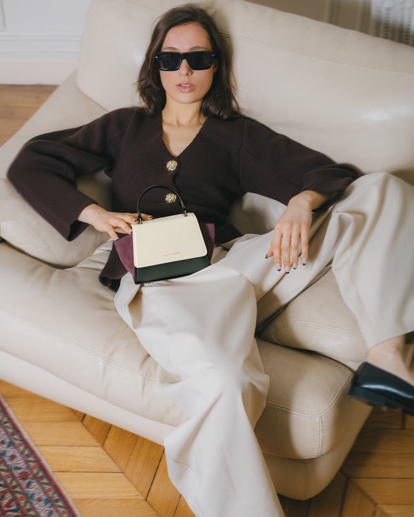Sac ALEXIA NANO Colourblock Canopé tenu par la poignée, posé sur les genoux d'une femme assise
