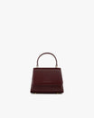 Sac ALEXIA NANO Mahogany de face, rabat fermé, poignée rigide relevée, posé sur fond blanc