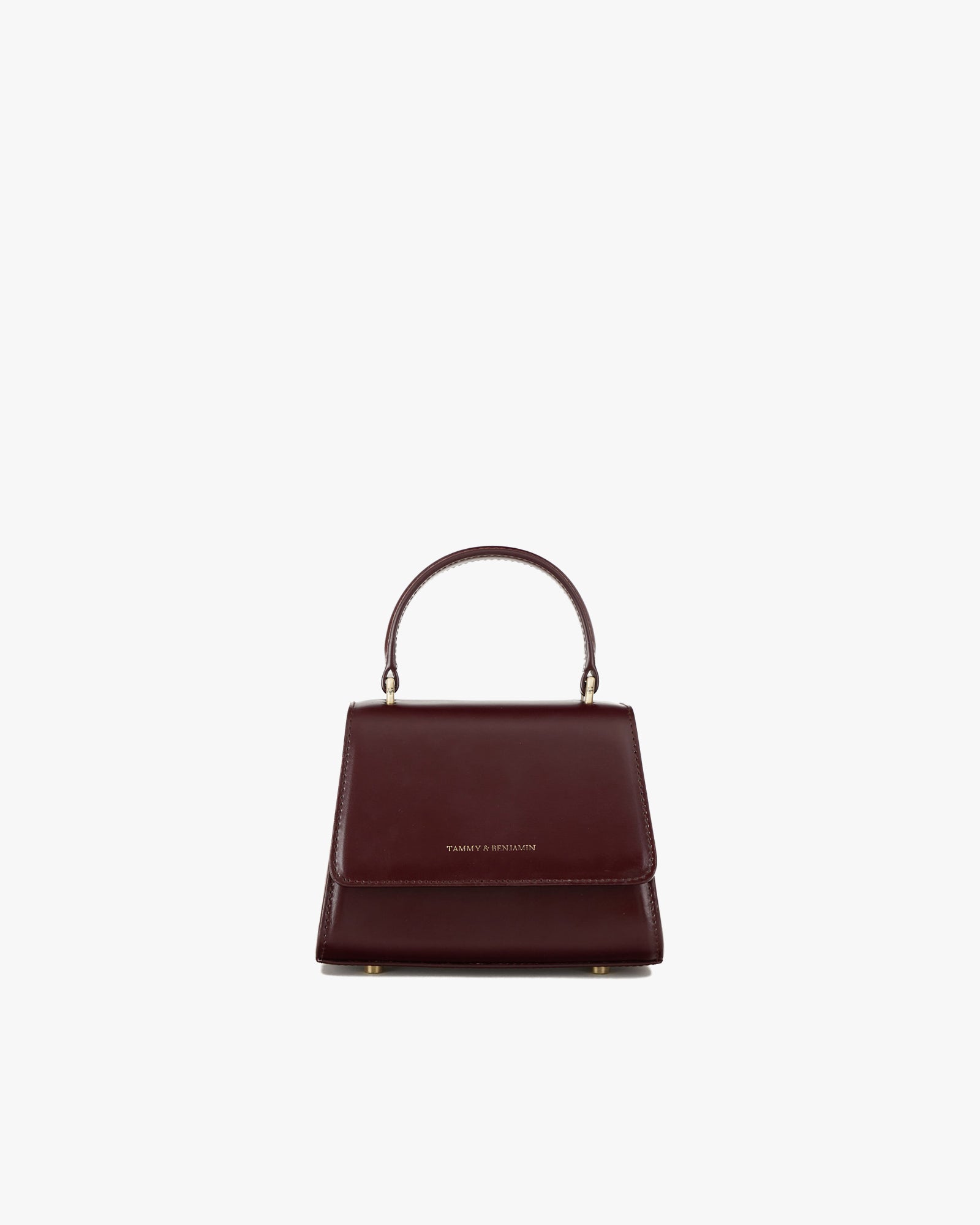 Sac ALEXIA NANO Mahogany de face, rabat fermé, poignée rigide relevée, posé sur fond blanc