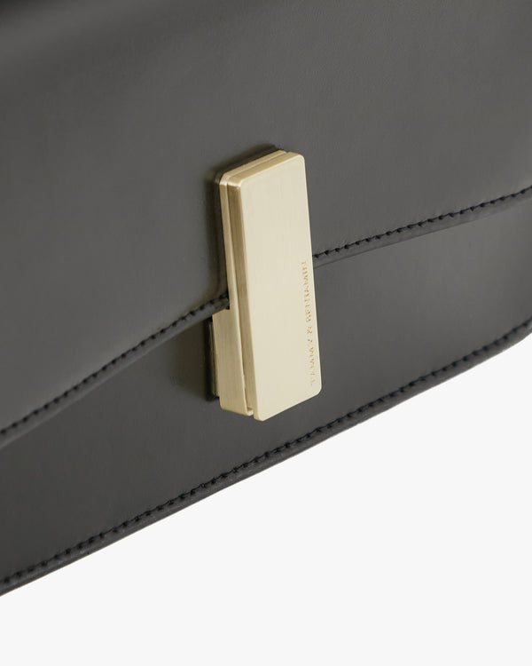 Sac BLAKE Noir, gros plan sur le fermoir doré et la couture de la patte