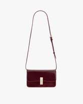 Sac BLAKE Mahogany de face, posé, fermoir doré et bandoulière fine ajustable déployée