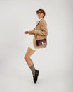 Sac BLAKE Mahogany porté en bandoulière, vue de profil sur une femme en veste à carreaux