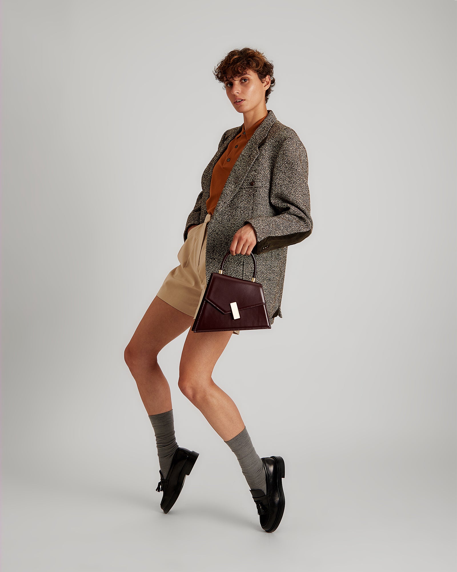 CUBIST Mahogany bag held by hand, gold clasp visible, full-length shot