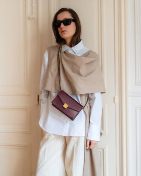 ELEANOR bag in Aubergine worn crossbody, gold Marble Arch clasp, styled with beige and white outfit