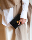 Sac ELEANOR Noir tenu à la main, fermoir doré Marble Arch en détail