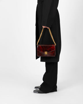 Sac ELEANOR Marbre porté à la main par sa chaîne dorée, vue de profil sur un modèle