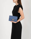 Pochette ELEANOR Bleu tenue à la main, fermoir doré Marble Arch, motif imprimé
