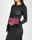 Pochette ELEANOR Bordeaux tenue à la main, fermoir doré Marble Arch, portée devant une robe noire
