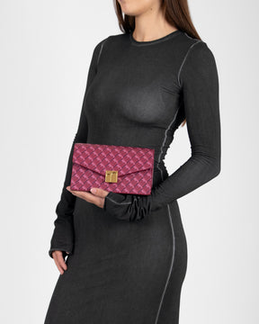 Pochette ELEANOR Bordeaux tenue à la main, fermoir doré Marble Arch, portée devant une robe noire