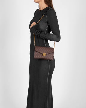 ELEANOR bag in Chocolat monogram worn on the shoulder with chain, side view on model