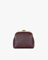 Sac EMMA en cuir aubergine, vue de face, posé, fermoir doré, sans bandoulière