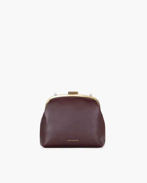 Sac EMMA en cuir aubergine, vue de face, posé, fermoir doré, sans bandoulière