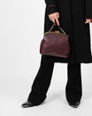 Sac EMMA Aubergine porté à la main, fermoir doré, poignée courte en cuir