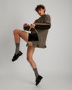 GABRIELLE bag in black naplak leather, held by hand via its gold chain, model in dynamic pose