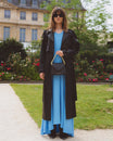 Sac GABRIELLE Noir porté à la main par une mannequin, avec chaîne dorée, en extérieur