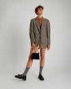 GABRIELLE bag in black naplak leather held by hand with short gold chain, full-length shot