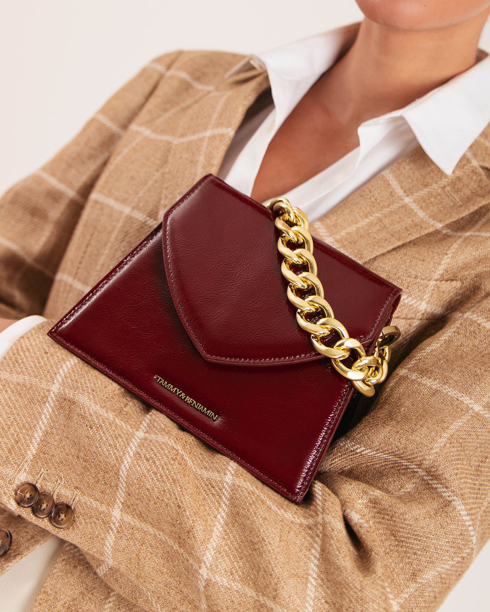 GABRIELLE bag in Bordeaux naplak carried under the arm, close-up on the pointed flap and gold chain