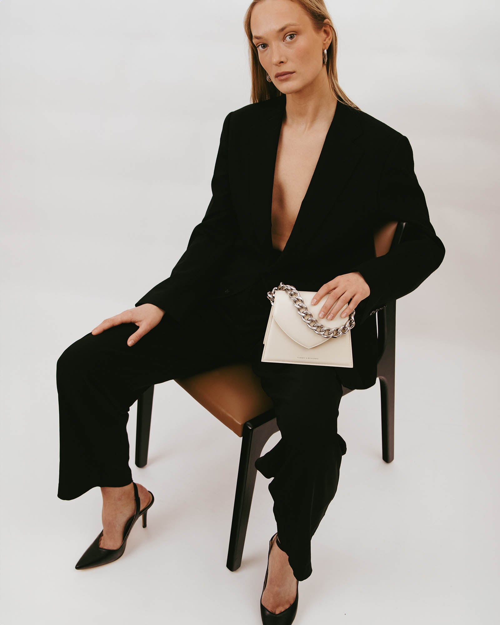 GABRIELLE bag in Ivory held in hand, seated pose, detachable short chain visible
