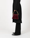 Sac GABRIELLE Mahogany porté à la main par la anse chaîne dorée, vue de profil