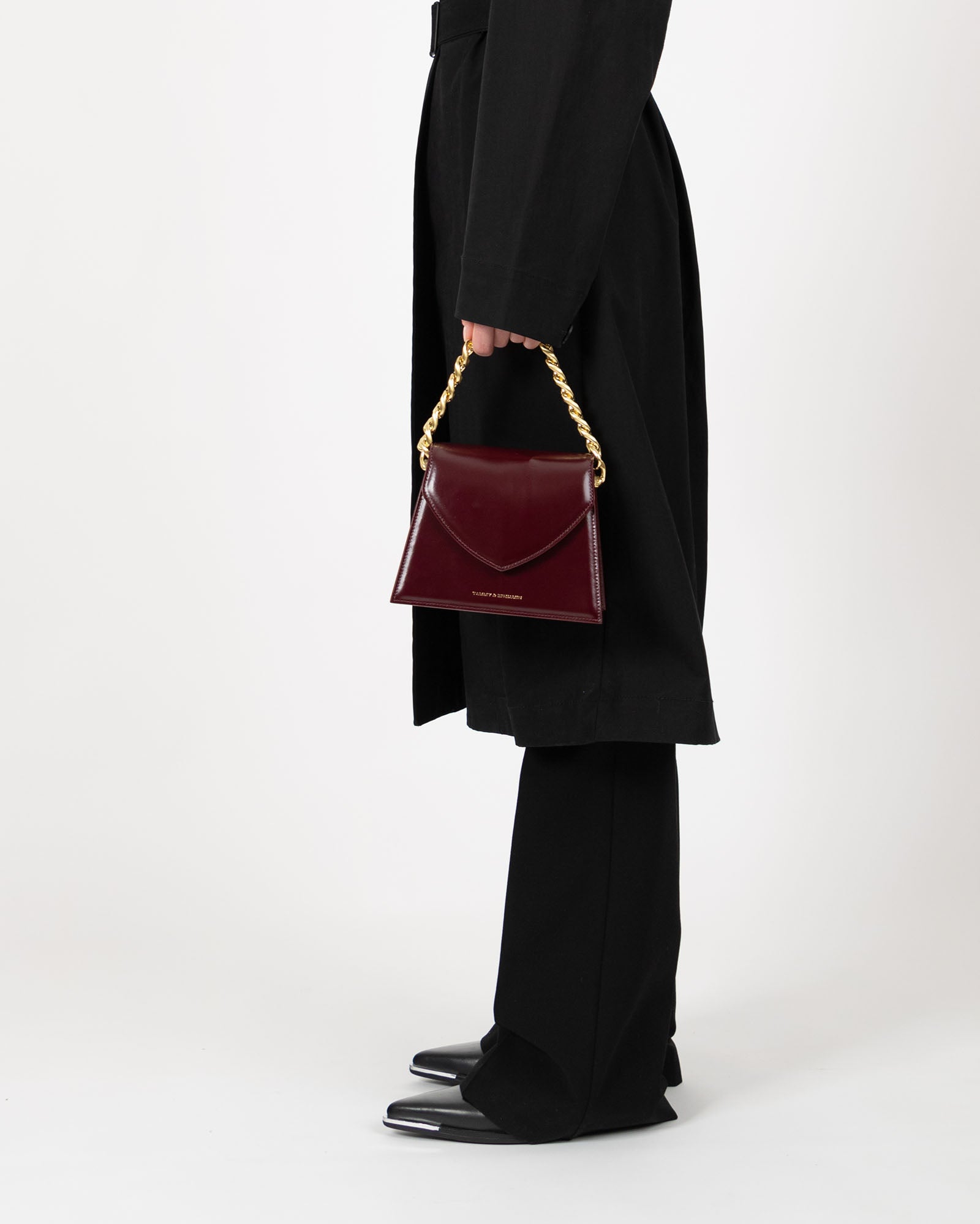 Sac GABRIELLE Mahogany porté à la main par la anse chaîne dorée, vue de profil