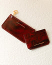 Pochette zippée et porte-cartes CARDY en cuir marbre bordeaux, posés côte à côte